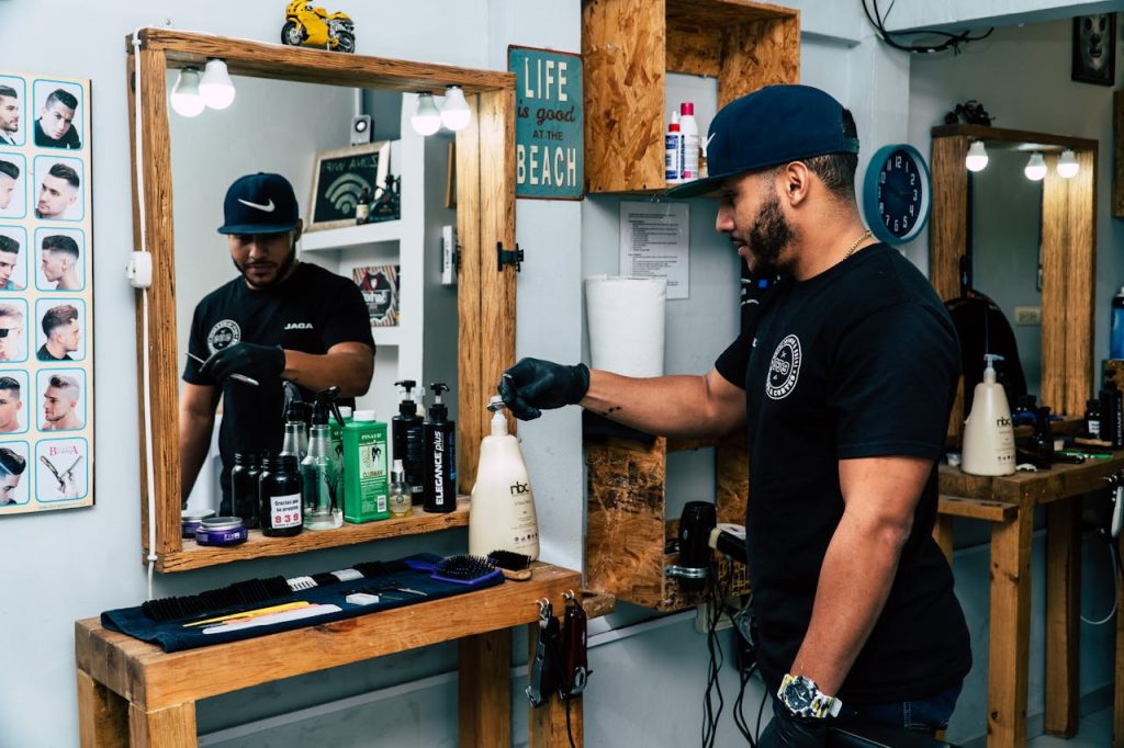 A barber in a stylish shop preparing tools for a haircut. Modern interior design with mirrors and grooming products.